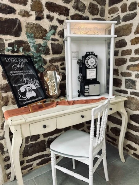 Coin livre d’or audio : téléphone vintage dans une niche blanche sur une console, devant un mur en pierre