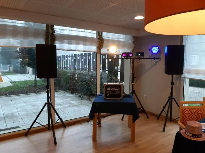 Installation DJ virtuel dans une salle : enceintes sur pieds, jeux de lumière et pupitre de commande