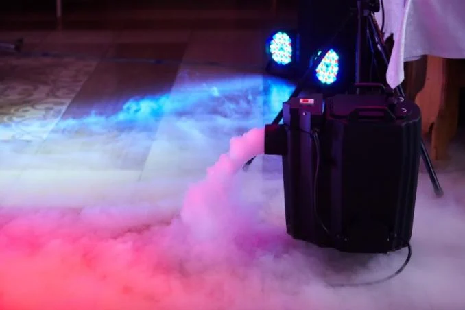 Machine à fumée lourde diffusant un brouillard au sol éclairé en rose et bleu