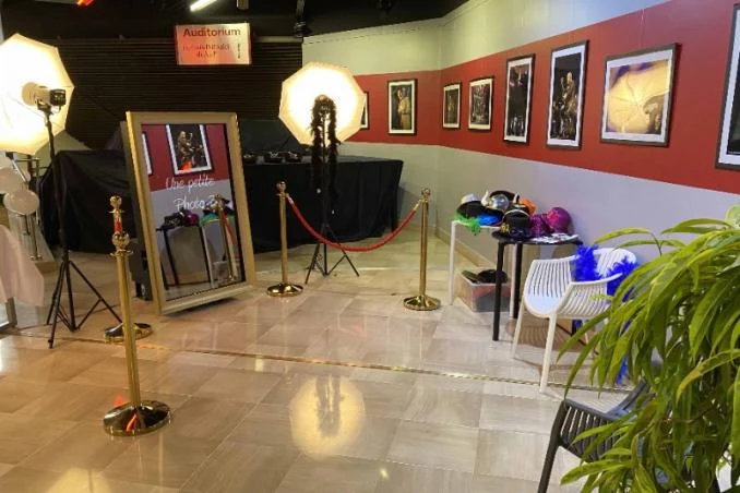 Photobooth miroir à cadre doré installé dans une salle de réception, avec éclairages et accessoires