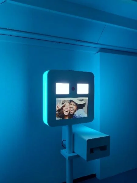 Borne photobooth blanche à écran éclairé, sous une lumière bleue