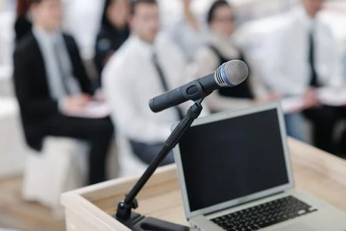 Pupitre de conférence avec micro et ordinateur portable devant un public
