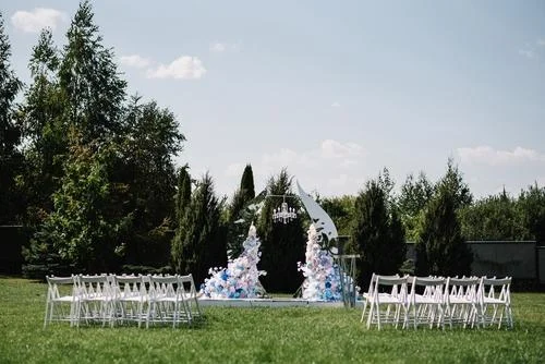 Cérémonie de mariage en extérieur avec chaises blanches et arche fleurie
