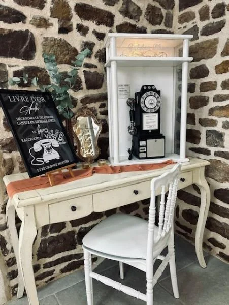 Coin livre d’or audio : téléphone vintage noir dans une niche blanche sur une console, devant un mur en pierre
